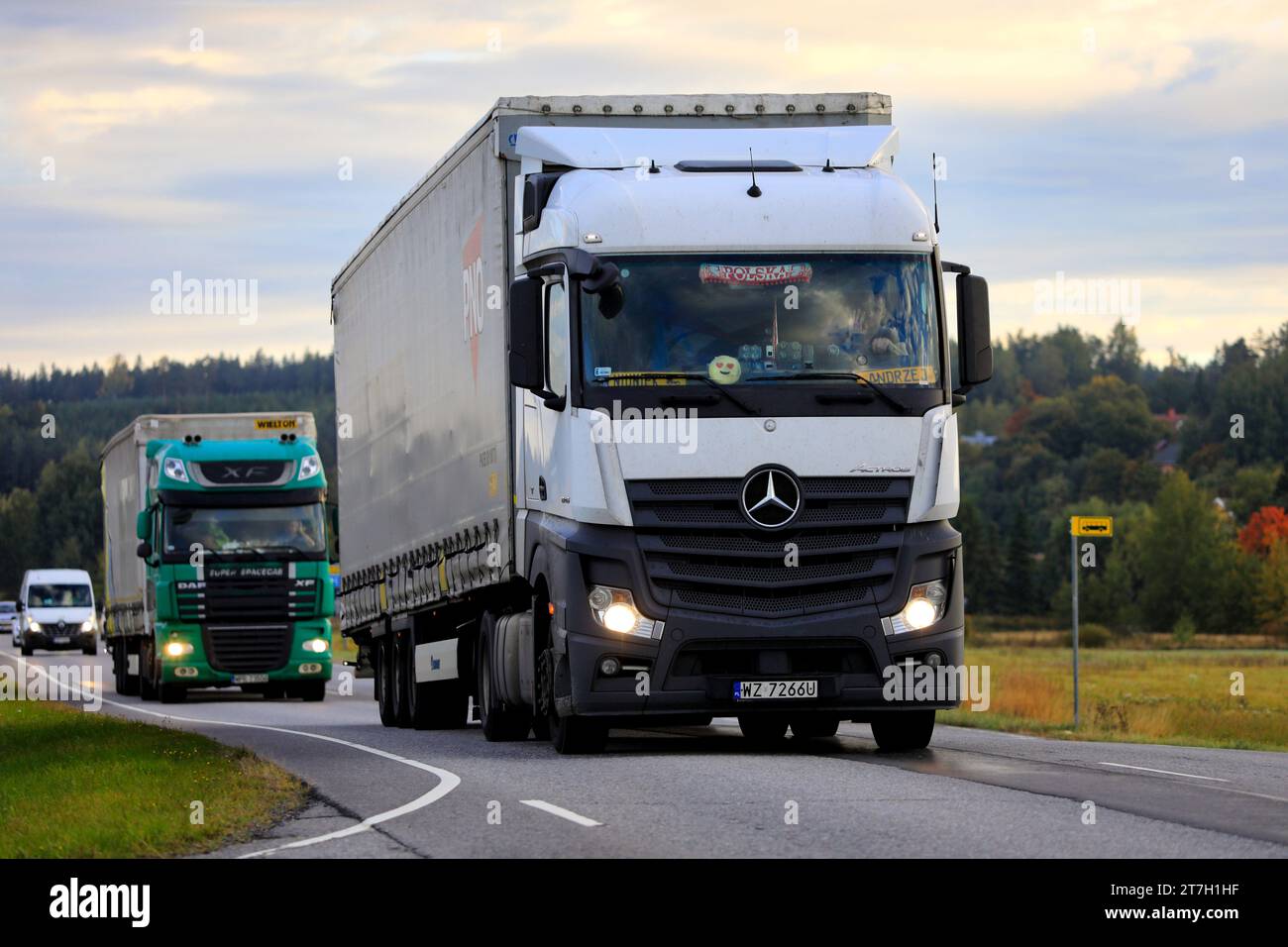 White Mercedes-Benz Actros and DAF freight trucks, Poland plates, pull trailers along Highway 52 early in autumn morning. Salo, Finland. Sept 23, 2022 Stock Photo