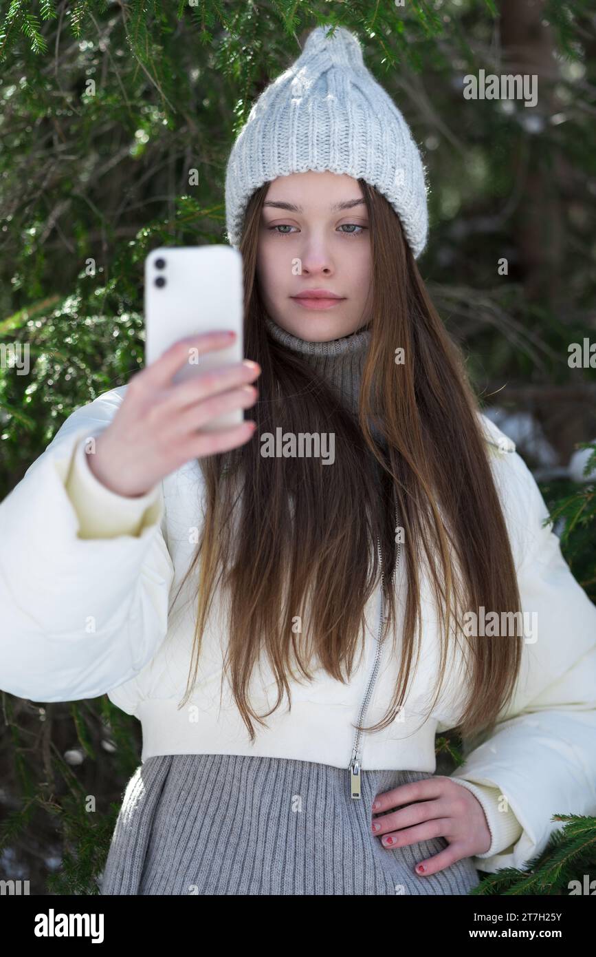 Teen girl 17 year old using cell phone in vertical orientation, shooting video to send to social networks through mobile application Stock Photo