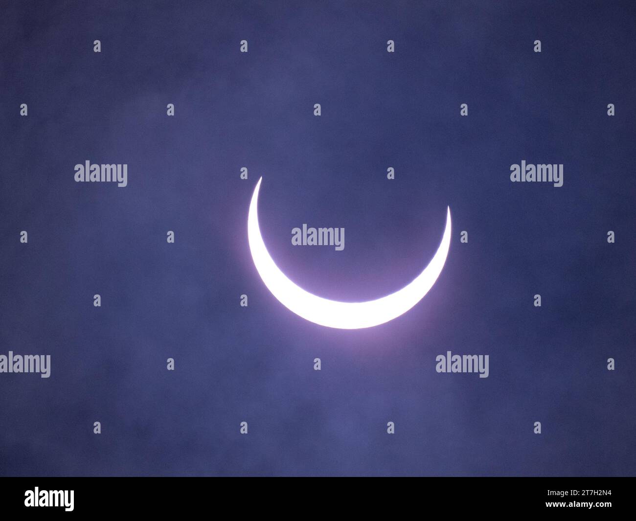 Evolving annular eclipse of the sun by the moon with thin clouds in the ...