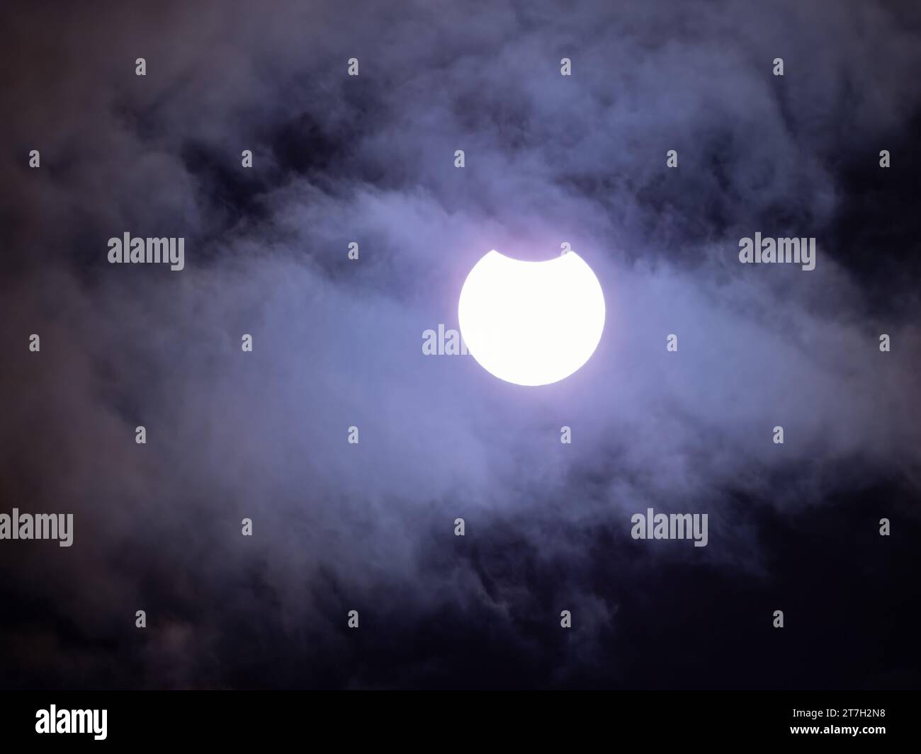 Partial solar eclipse by the moon with clouds in front of the sun ...