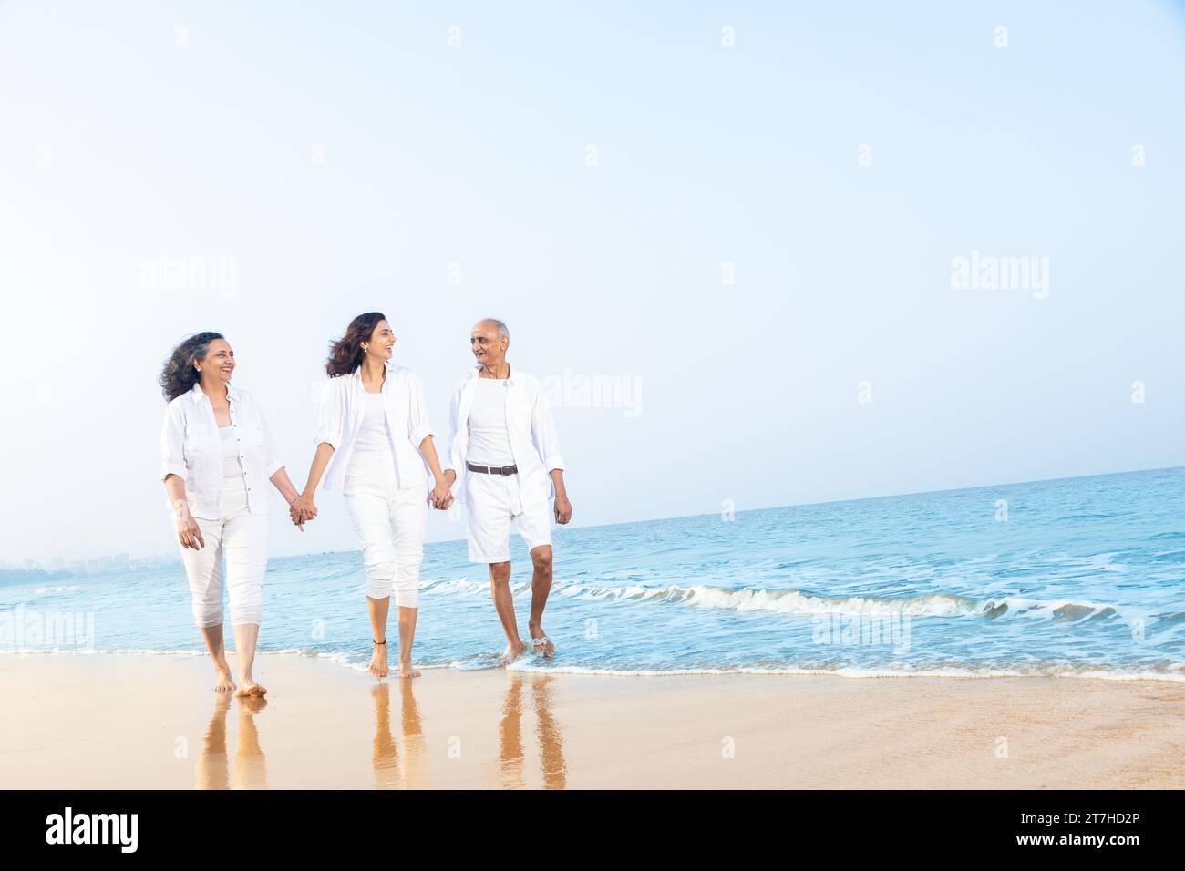 Happy senior indian couple with beautiful young daughter enjoying vacation at beach. Stock Photo