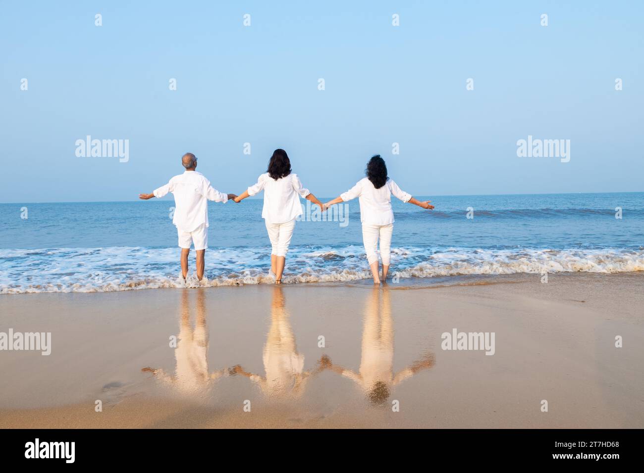 Happy senior indian couple with beautiful young daughter posing and enjoying vacation at beach. Stock Photo
