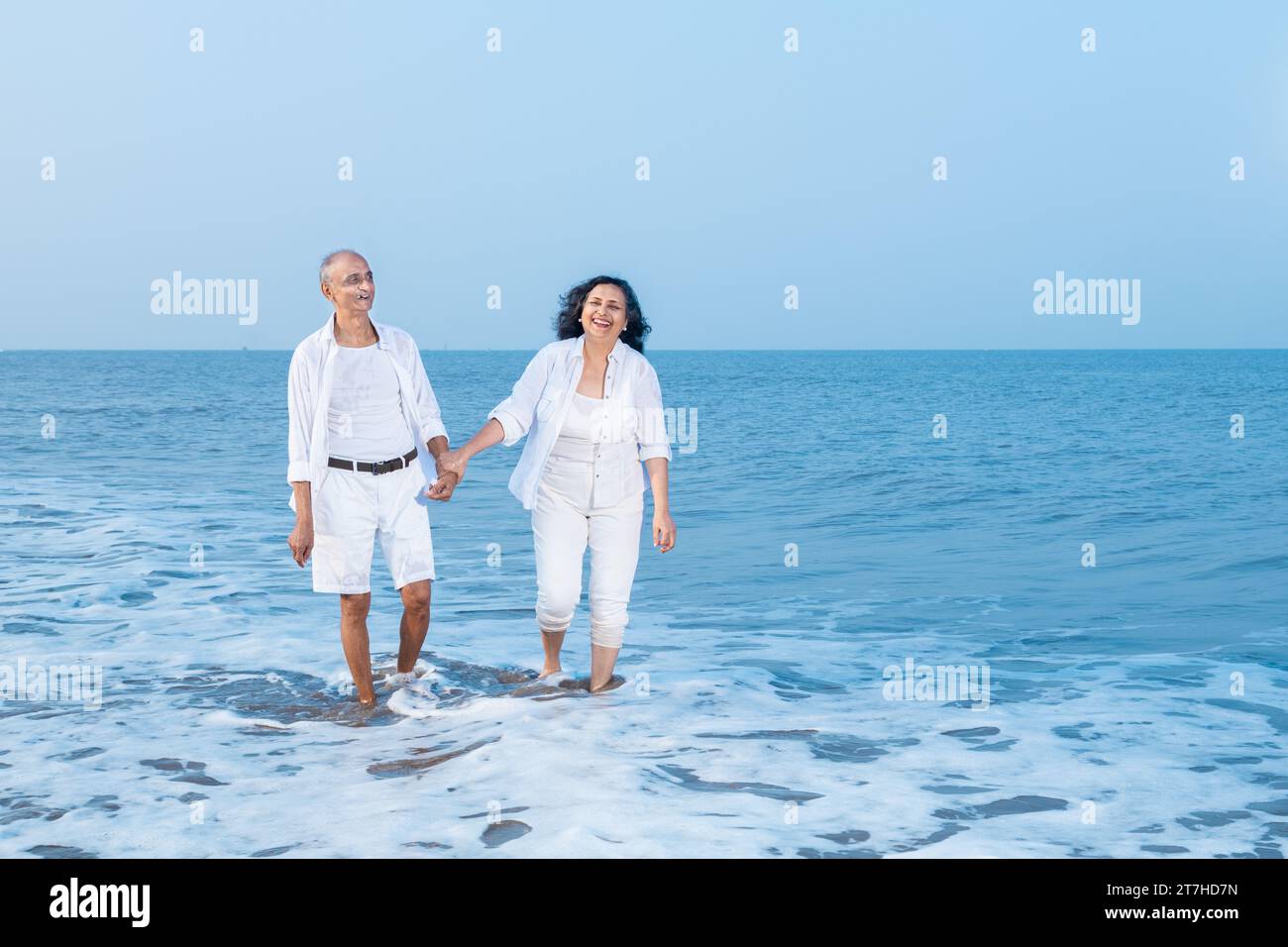 Happy senior indian couple walking together and enjoying summer vacation, holiday at beach. Stock Photo