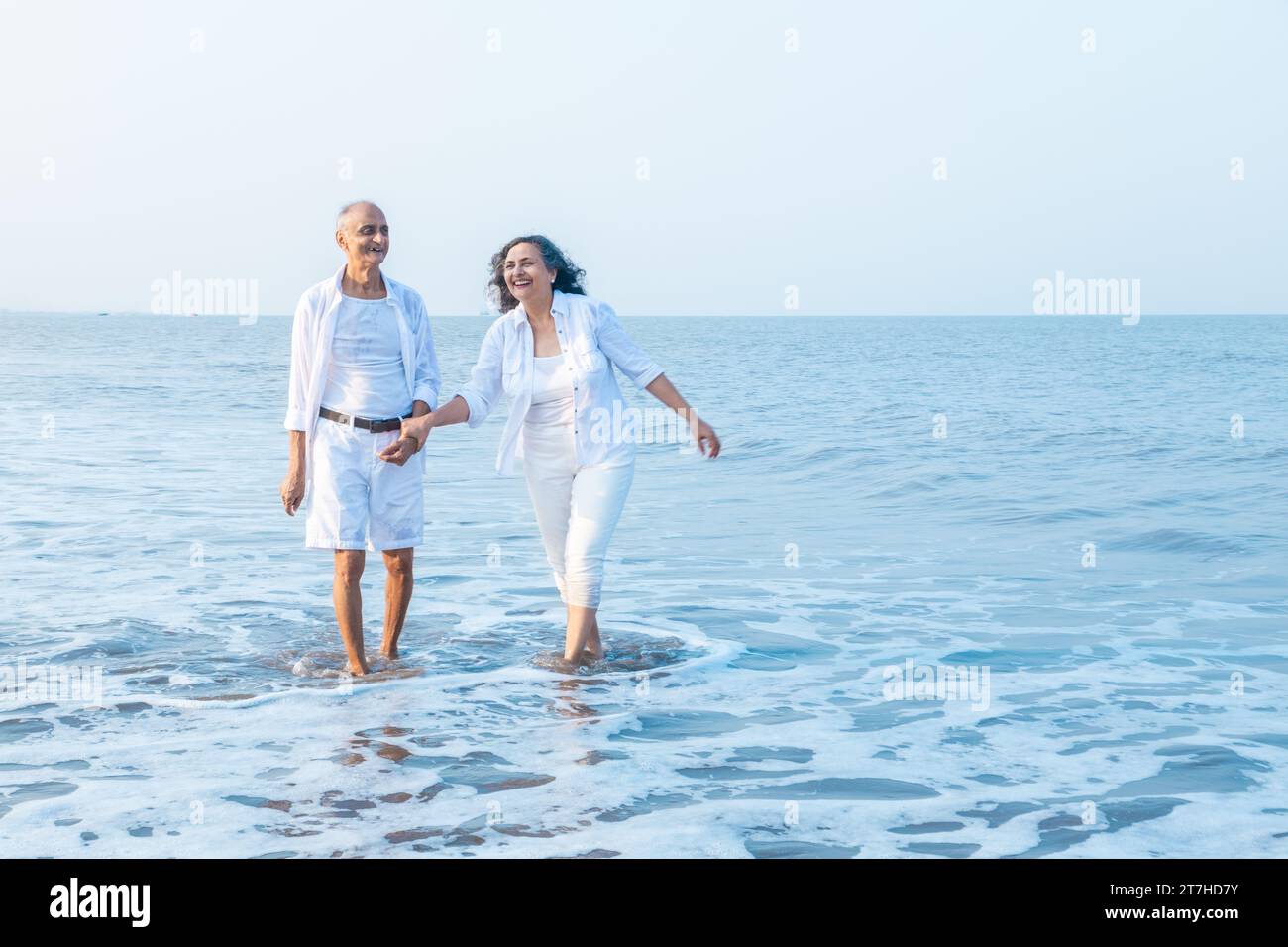 Happy senior indian couple walking together and enjoying summer vacation, holiday at beach. Retirement life. Stock Photo