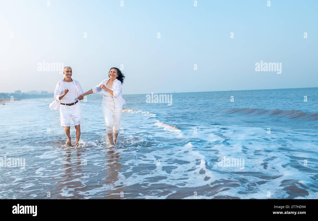 Happy senior indian couple enjoying summer vacation, holiday at beach. Copy space Stock Photo