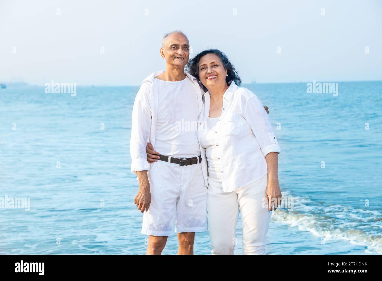 Happy senior indian couple wearing white cloths enjoying summer vacation, holiday at beach. Stock Photo