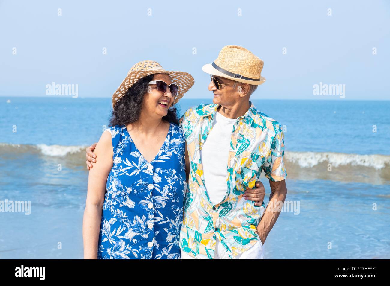 Senior indian couple with colorful balloon in hands running together at the beach. Enjoying vacation, holiday at beach. Copy space. Retirement life. Stock Photo