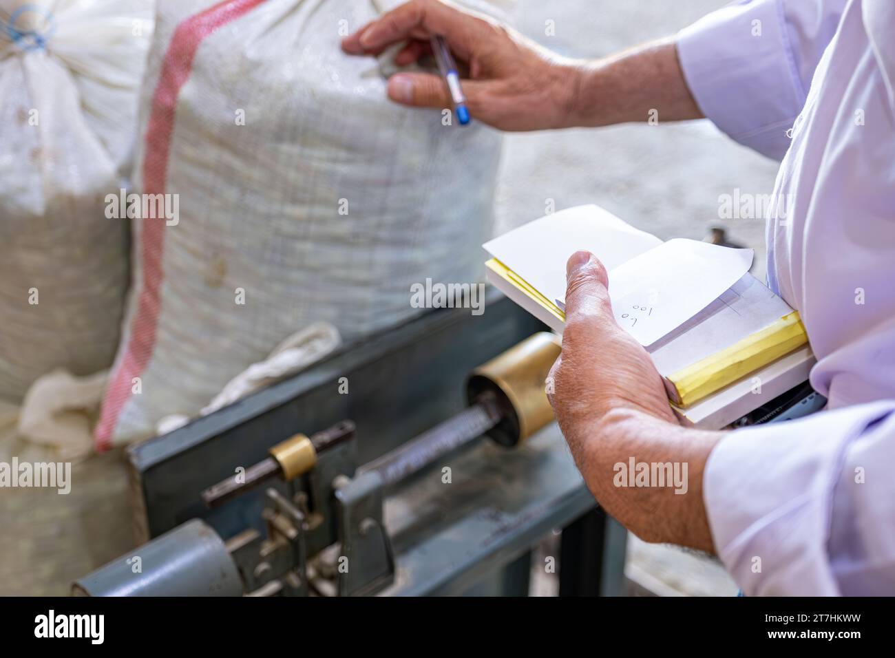 man handsholding pen in front of scale weighing packs ,weighing sacks