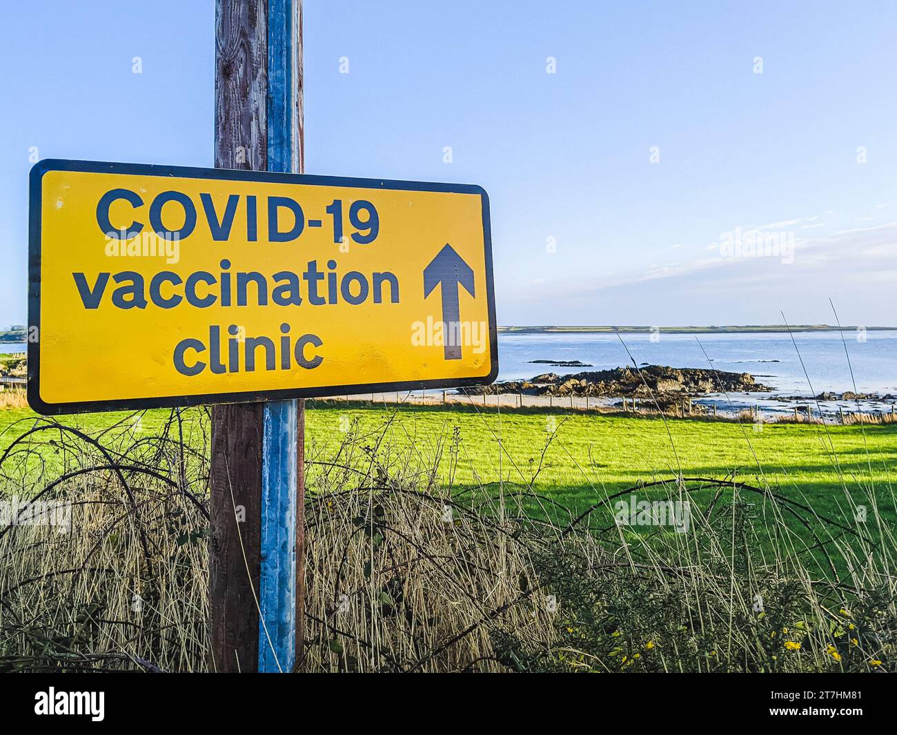 Sticker placed by a protester saying 'No apartheid, no vax mandates' on a sign directing people to COVID-19 vaccinatino clinic. Stock Photo