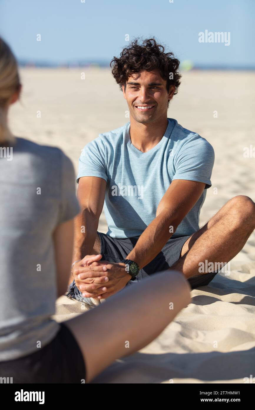 couple meditating on beach from back Stock Photo