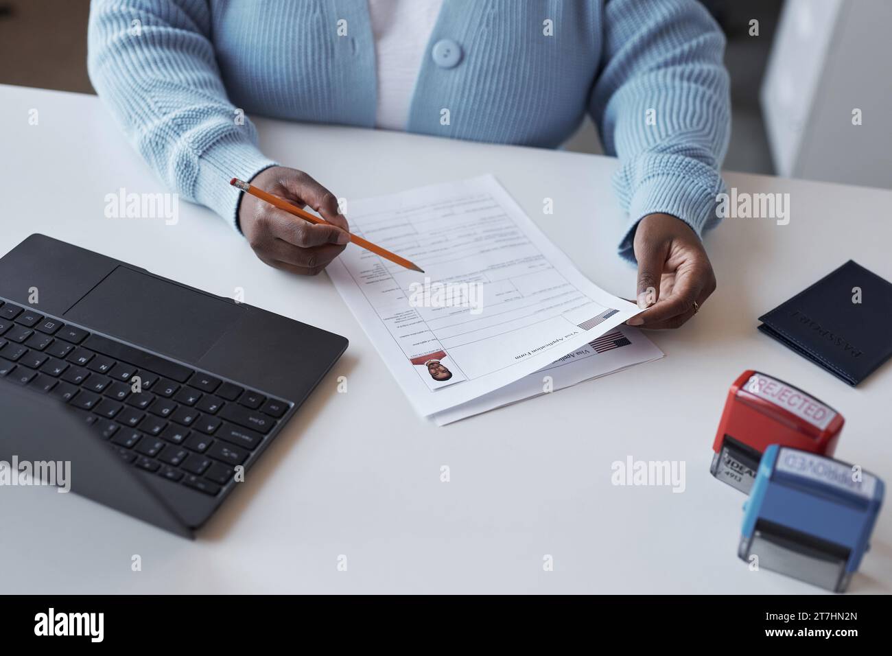 Hands of young female worker of visa center with pencil over document checking personal data of applicant before before validating it Stock Photo