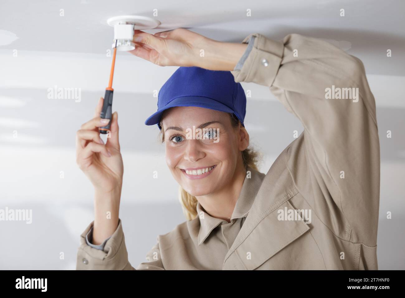 woman installing a light bulb in the ceiling Stock Photo