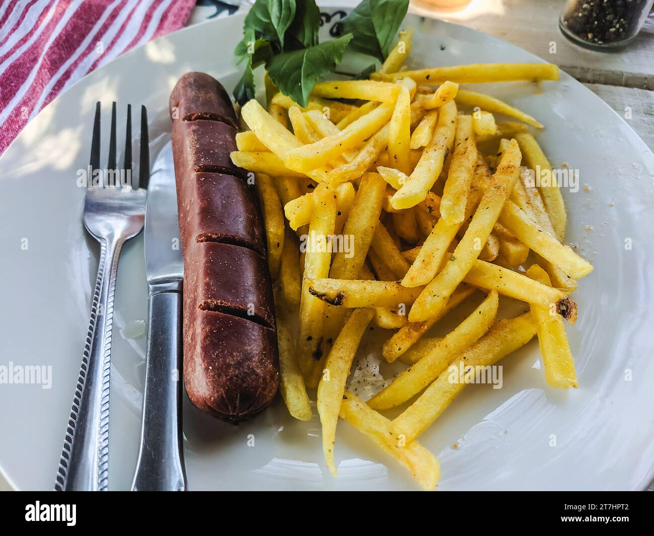 Cheap lunch in a restaurant in Otjiwarongo, Namibia of a kudu meat hotdog sausage and french fries chips. Stock Photo