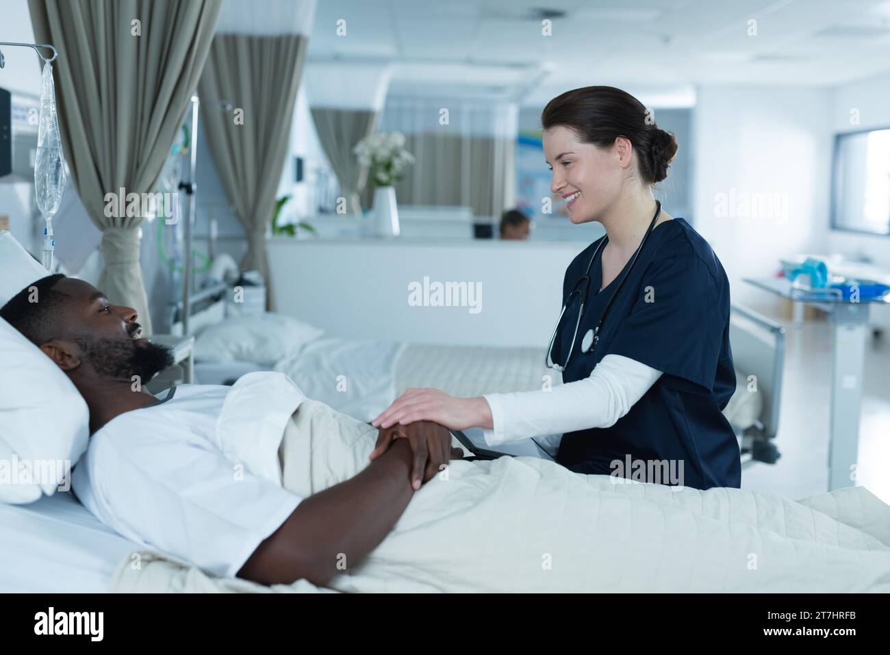Diverse female doctor and male patient is lying in bed talking in ...