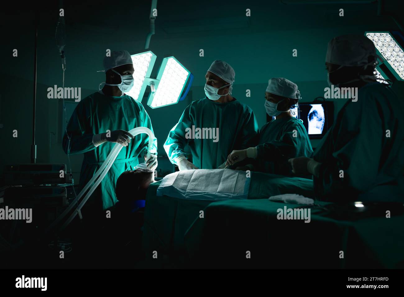 Diverse surgeons wearing surgical gowns operating on patient in operating theatre at hospital Stock Photo