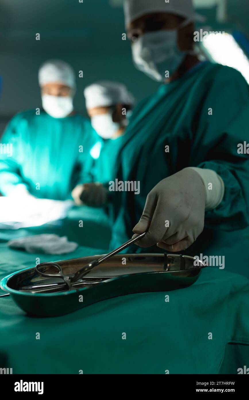 Diverse surgeons wearing surgical gowns using surgical instruments in
