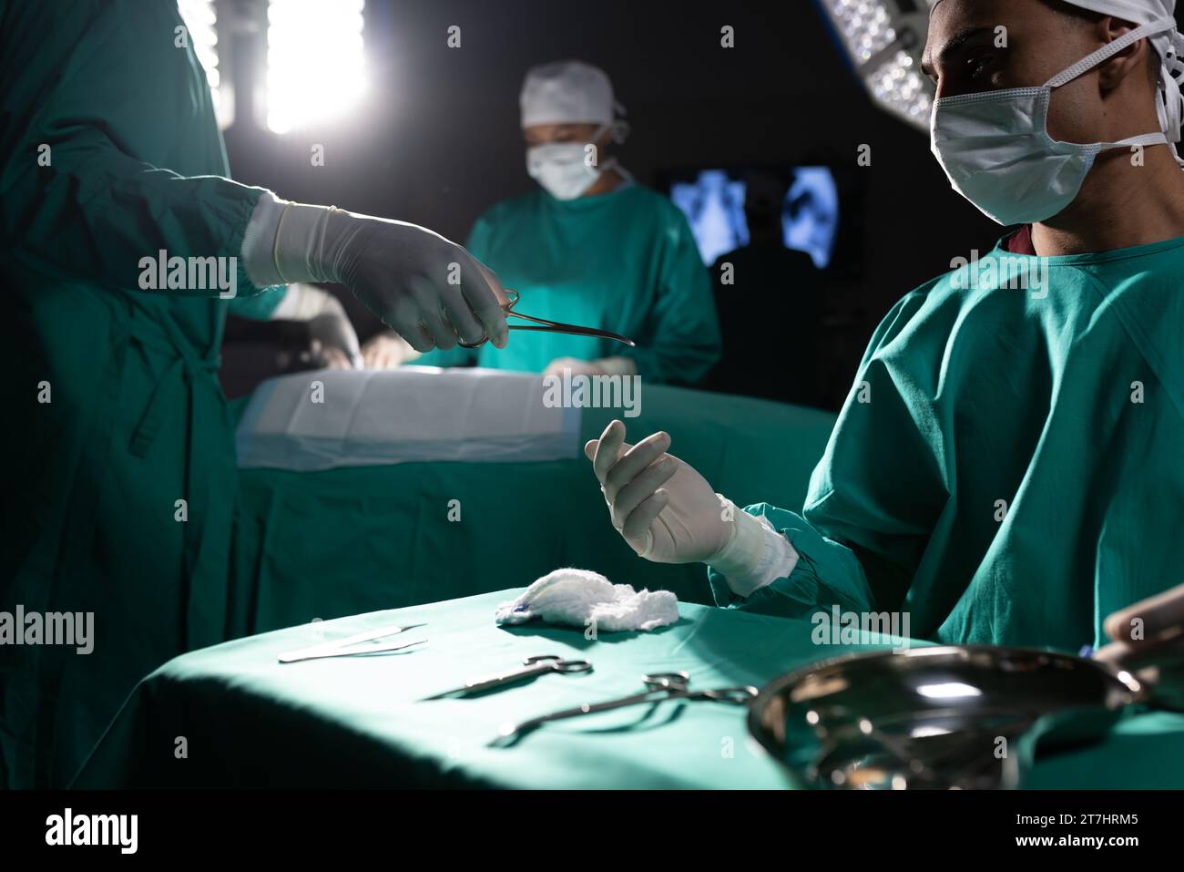 Diverse surgeons wearing surgical gowns using surgical instruments in