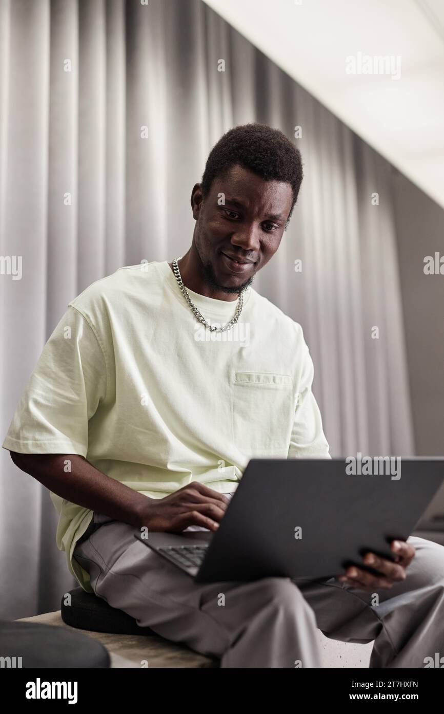 Minimal portrait of young African American man using laptop in office ...