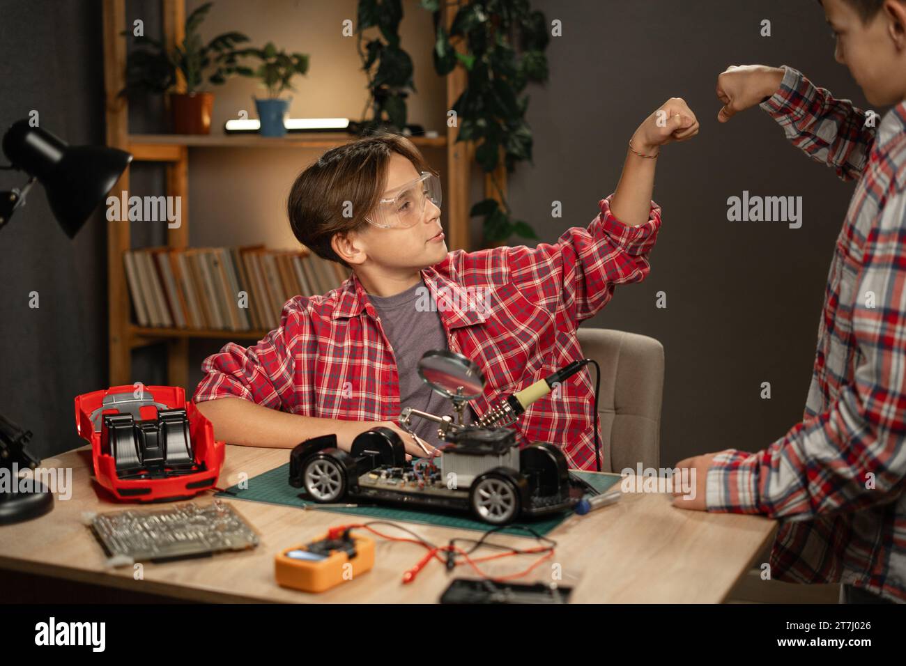 Young boys building robots and cars, using soldering iron to join chips and wires at home. Inventions and creativity for children Stock Photo