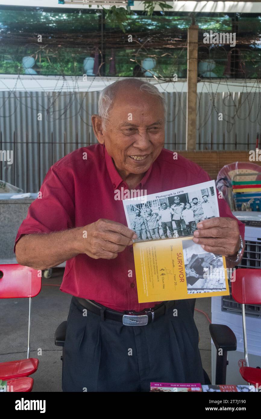 Chum Mey and his book in the courtyard of tuol sleng prison in phnom penh , cambodia Stock Photo
