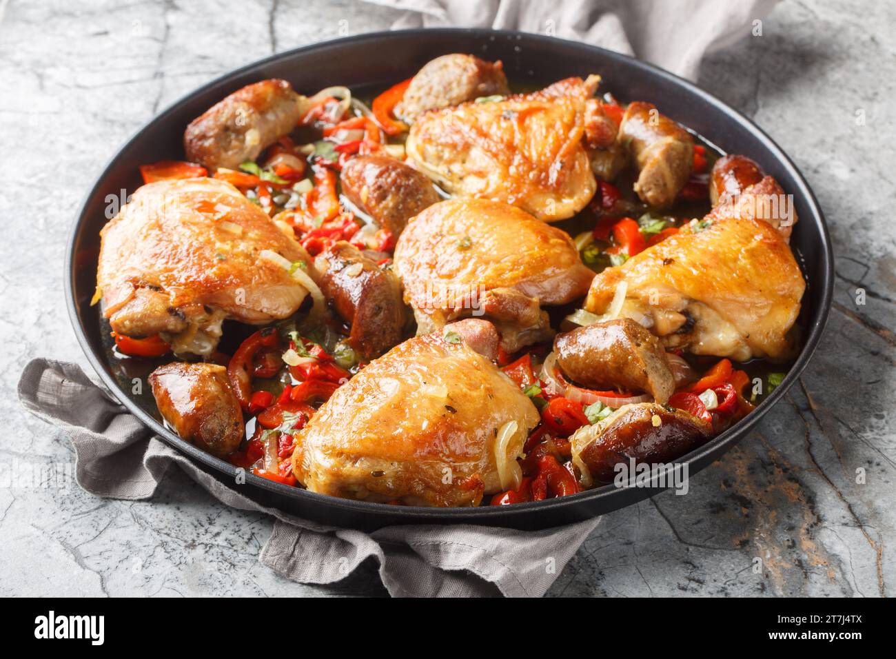 Braised chicken thighs, peppers and sausage in a vinegary, kind of spicy broth closeup on the