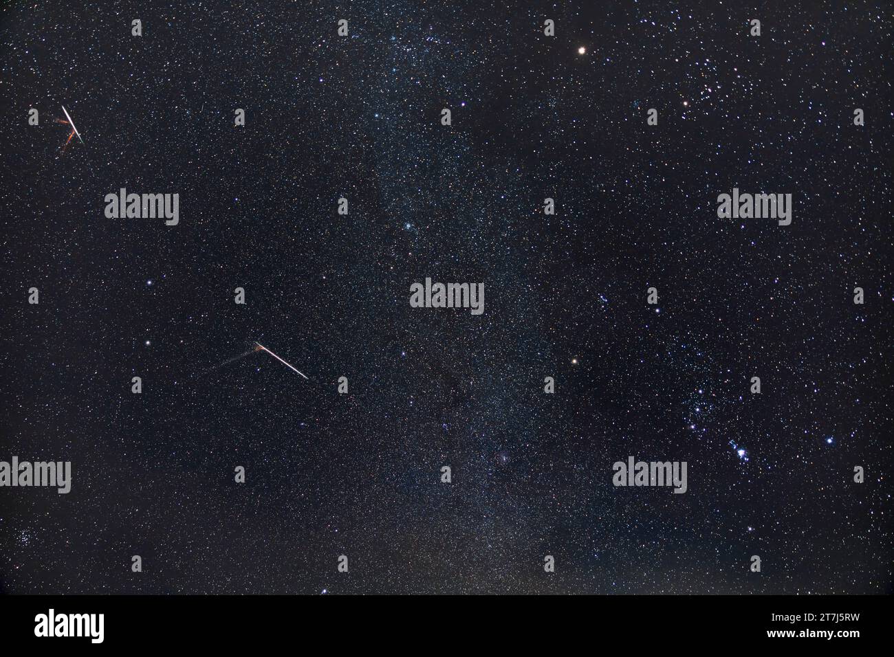 The Geminid meteor shower of 2022, showing two bright Geminids leaving yellowish ion trails or 'smoke' trains in their wake. The two meteors appeared Stock Photo