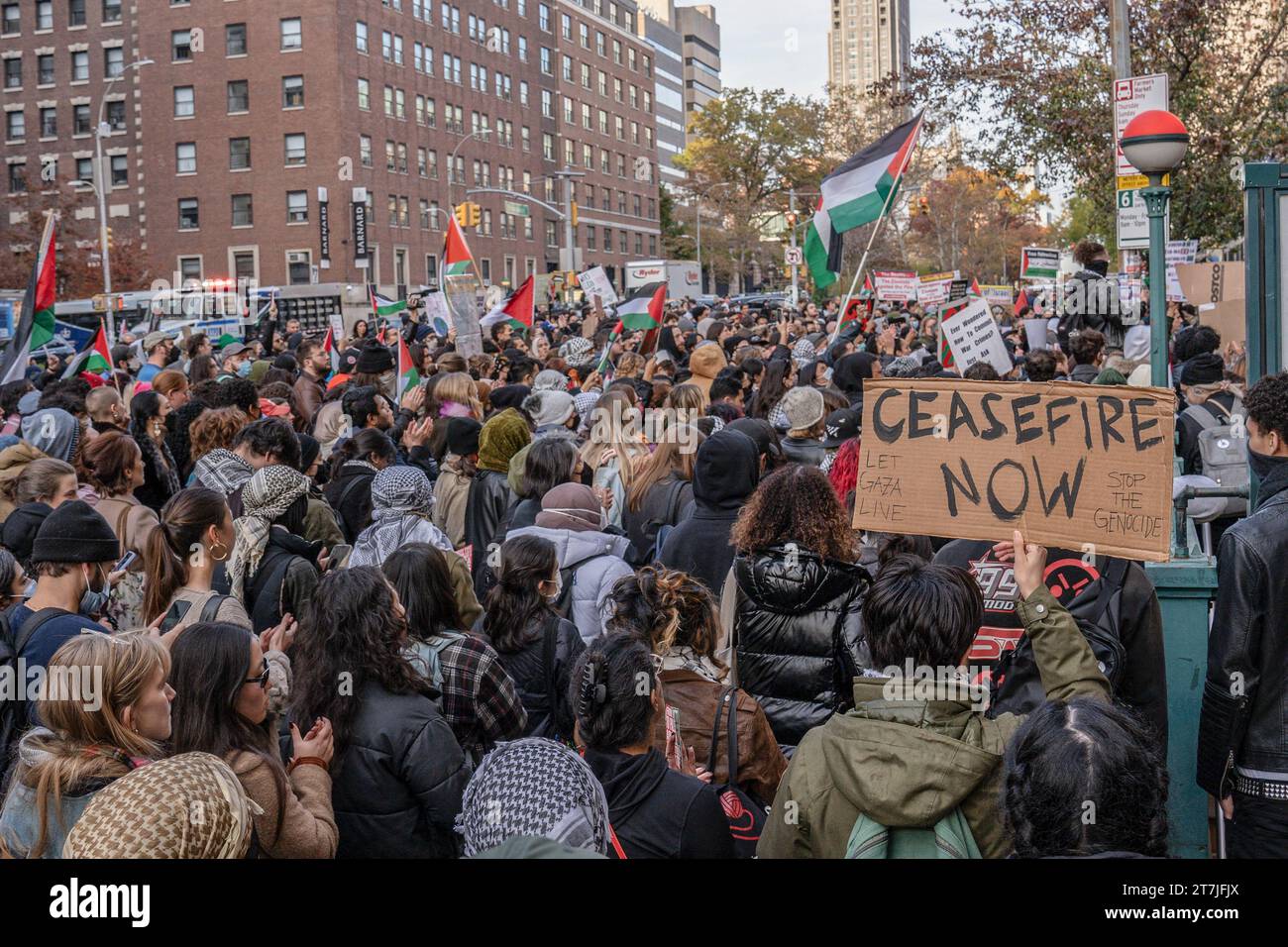 Manhattan, United States. 15th Nov, 2023. A protestor holds up a placard that says 'Ceasefire Now,' while in the crowd of other protesters waving Palestinian flags during the demonstration. Columbia University students hold a demonstration against the administration's suspension of two pro-Palestinian student groups, SJP and JVP. (Photo by Derek French/SOPA Images/Sipa USA) Credit: Sipa USA/Alamy Live News Stock Photo