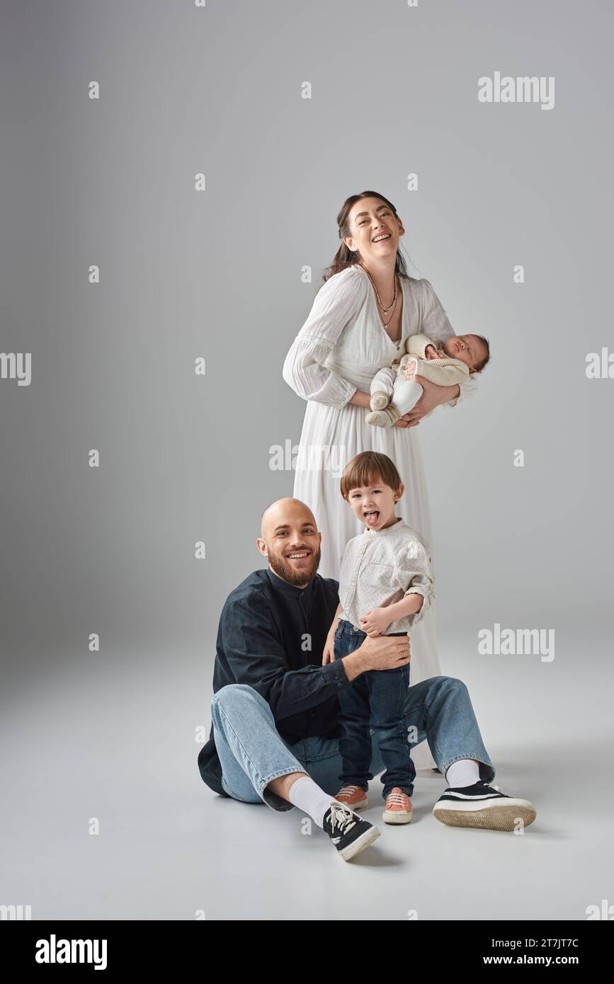 joyous mother holding her newborn baby while her husband sitting on ...