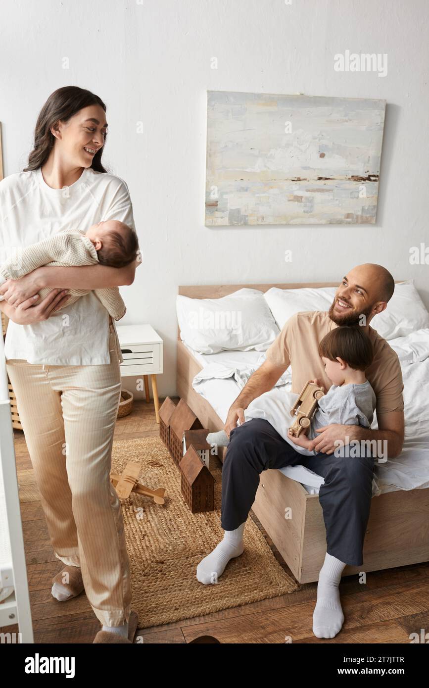 vertical shot of modern parents smiling happily at each other while spending time with children Stock Photo