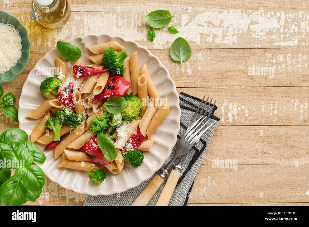 Wholegrain pasta penne with broccoli and red grilled bell pepper and on light wooden rustic background table. Vegan pasta. Traditional Italian cuisine Stock Photo
