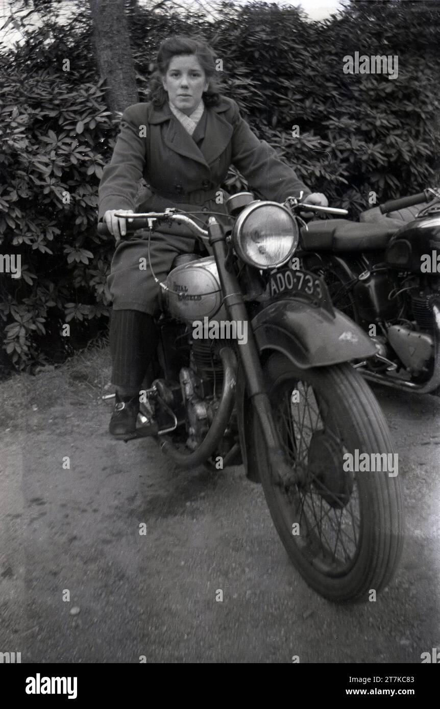 1950s, historical, a young woman sitting on a Royal Enfield motorcycle of the era, Oldham, Manchester, England, UK. Made by The Enfield Cycle Company, with the first one produced in 1901, loses from makiing motor cars, saw most of the company taken over in 1907 by BSA, a larger competitor.  Production of motorcycles under the Royal Enfield name continued at the Redditch manufacturing plant and in 1931 the famous 'Bulliet' was introduced. This model, with modifications, continued to be produced in Britain up to the mid 1960s. Stock Photo