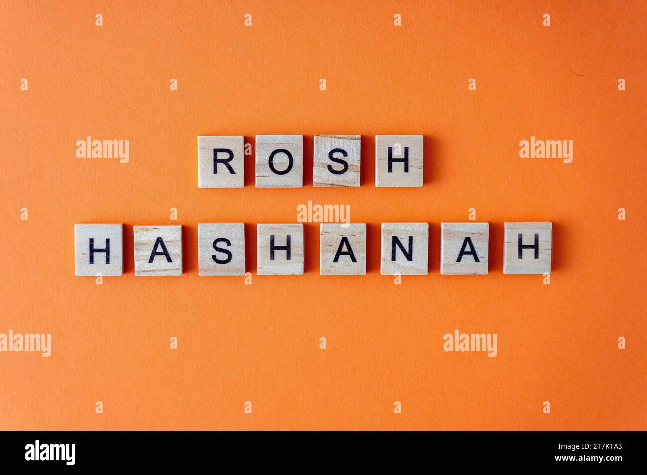 Rosh Hashanah word. The phrase is laid out in wooden letters top view. Orange flat lay background Stock Photo
