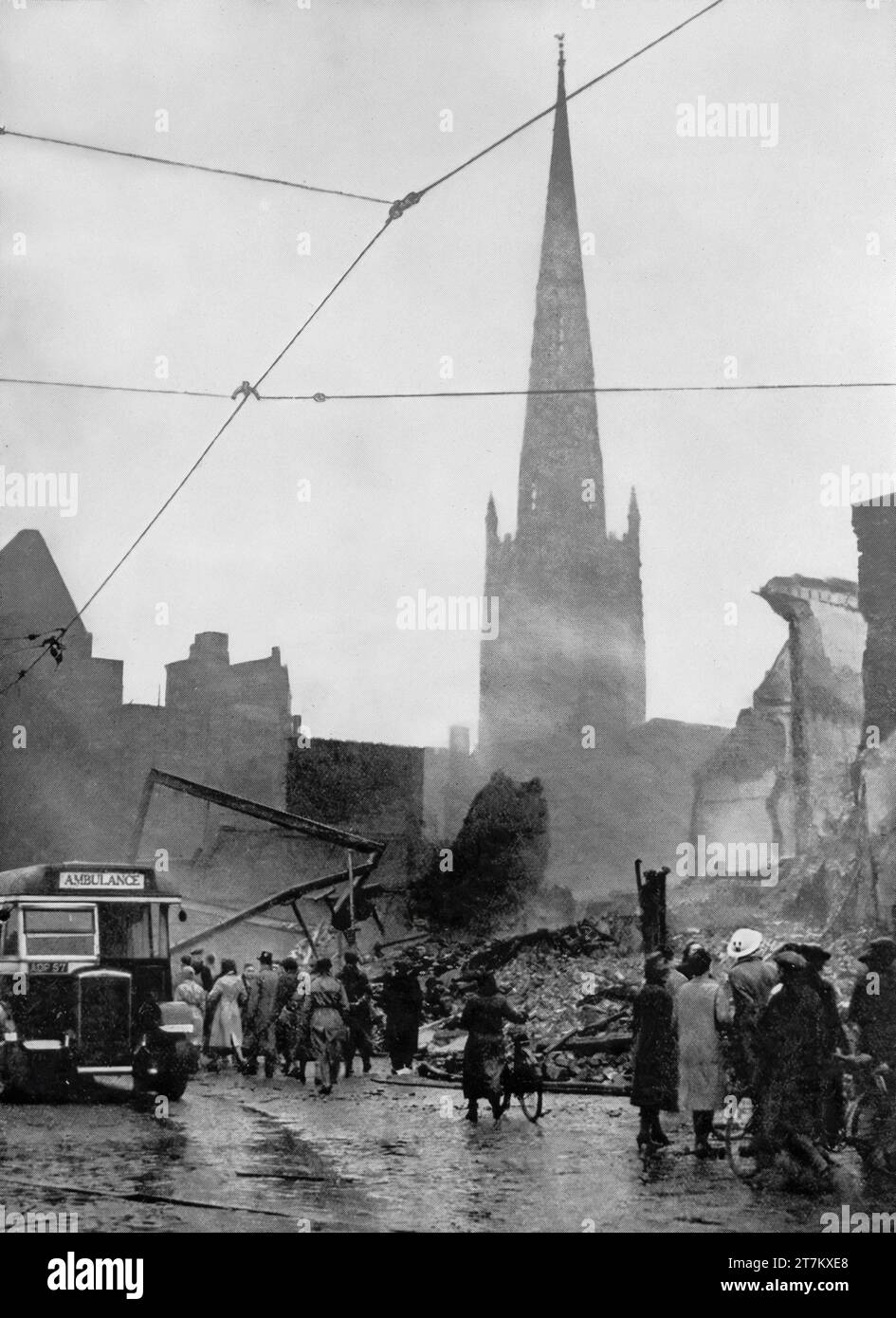 The morning of the 14th November 1940, and people in Coventry, England survey the damage caused by the previous nights Luftwaffe air raids during the Second World War. Happily the city's cathedral spire is still standing Stock Photo