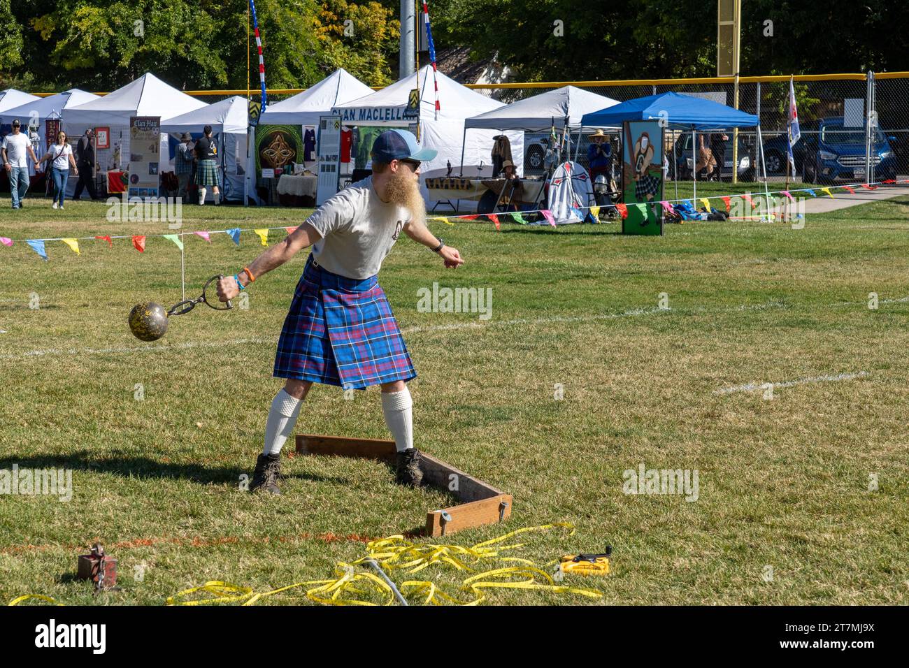 A competitor in a kilt throws the ball in the Highland games weight throw at the Moab Celtic Festival, Scots on the Rocks, in Moab, Utah.  The steel b Stock Photo