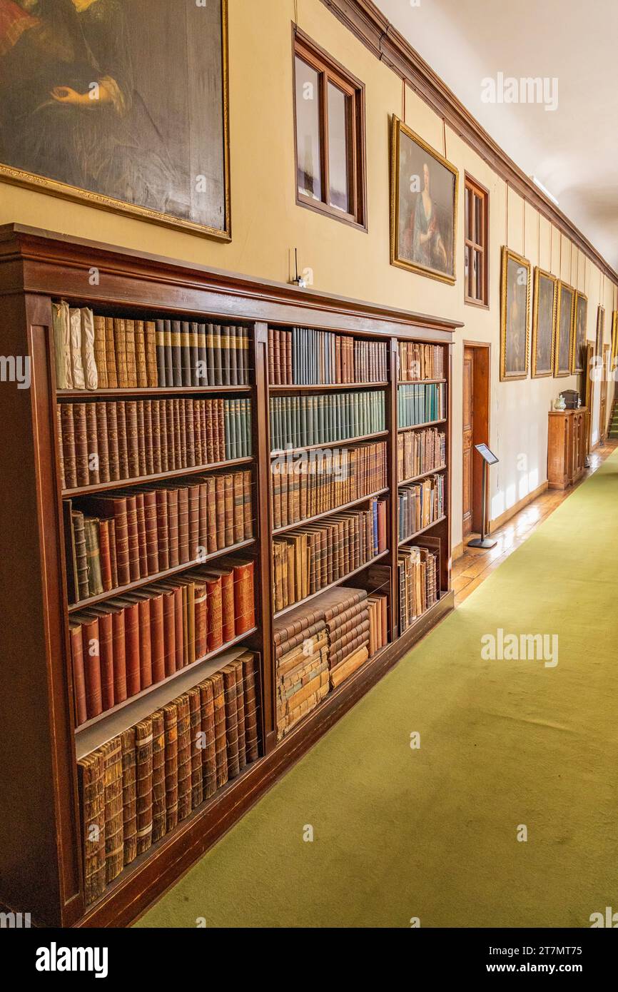 Wooden bookcase with neatly arranged books in a corridor at Lacock