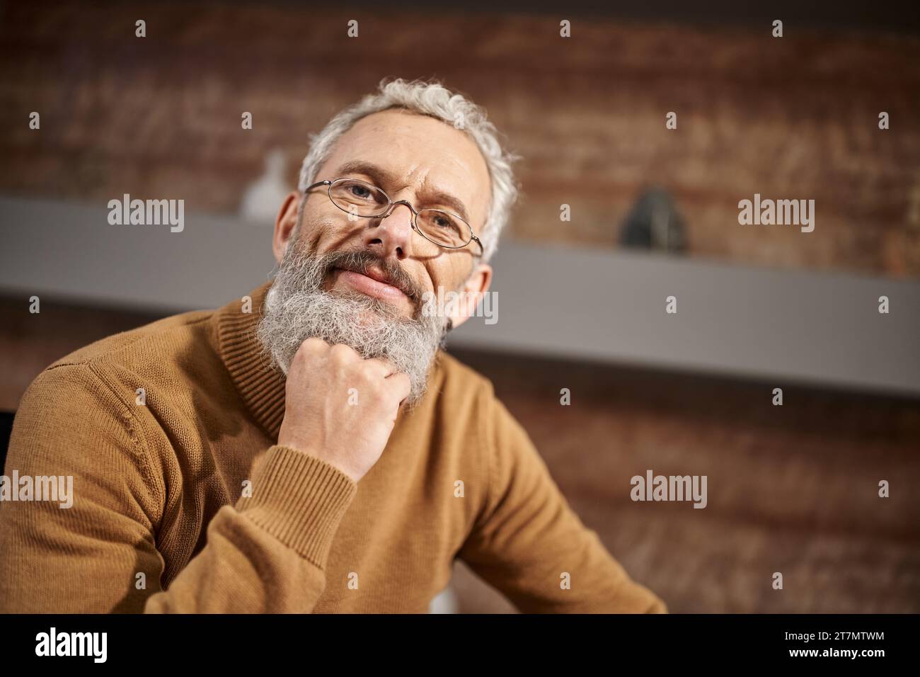portrait of handsome middle aged psychologist in glasses looking at camera during therapy session Stock Photo