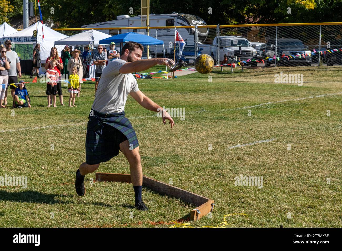 A competitor in a kilt throws the ball in the Highland games weight throw at the Moab Celtic Festival, Scots on the Rocks, in Moab, Utah.  The steel b Stock Photo
