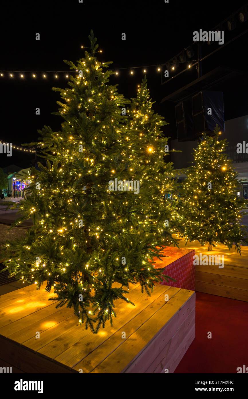 Christmas tree in pot with red decorations and lights outdoors near