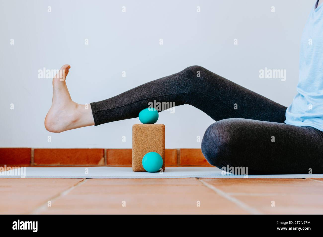 Woman doing calf muscle myofascial release with ball on cork block Stock Photo