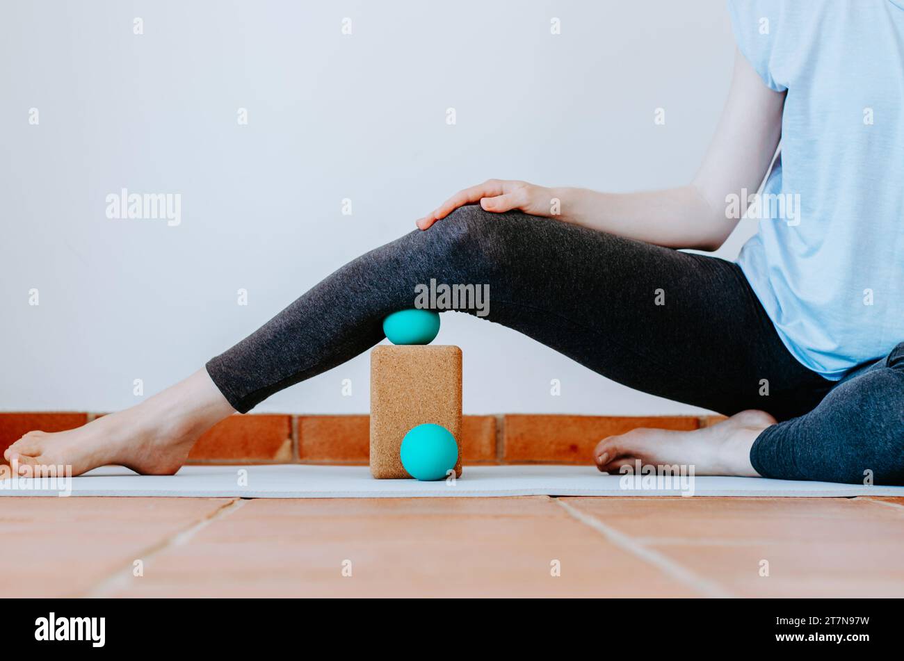 Woman doing calf muscle myofascial release with ball on cork block Stock Photo