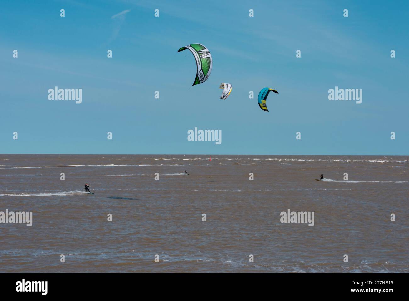 Windsurfers enjoy time on the water on a windy day in Shingle Street on the coast in Suffolk in England UK Stock Photo