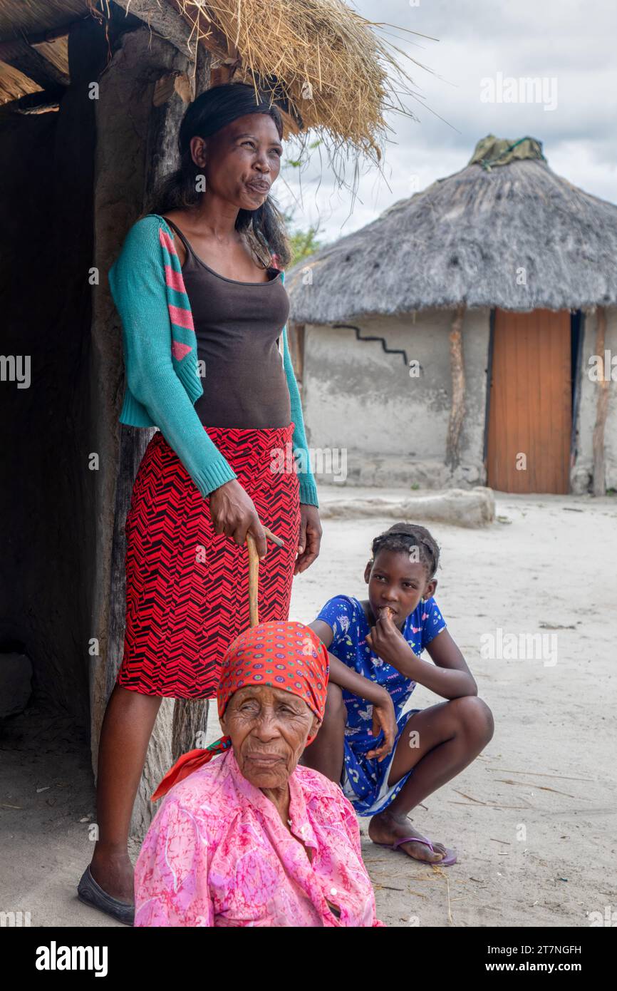 family of three, granny, mother and child, in front of the shack in the sandy back yard in a village in africa Stock Photo