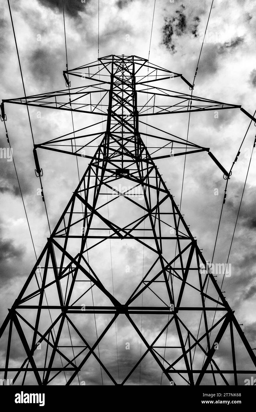 A dramatic low angle shot of a high voltage power tower under a cloudy