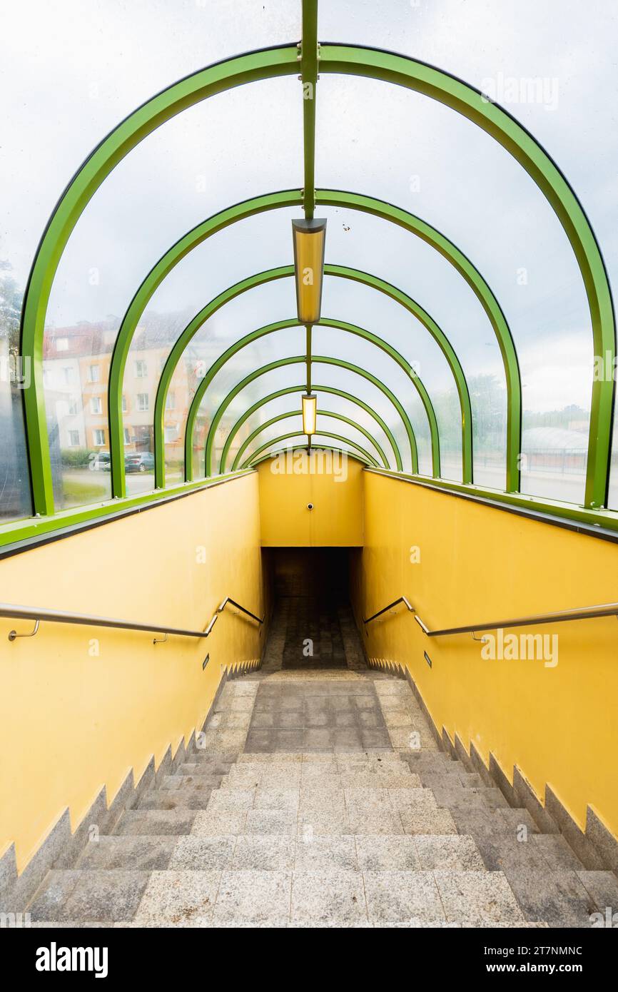 Small tunnel with yellow walls and green arcs and with downstairs to underground passage under streets Stock Photo