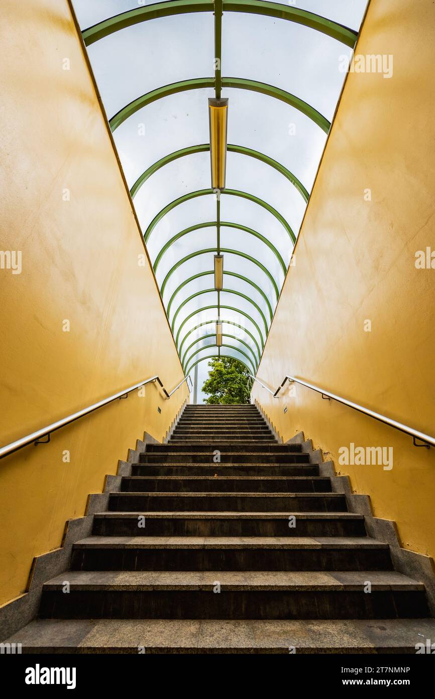 Small tunnel with yellow walls and green arcs and with downstairs to underground passage under streets Stock Photo