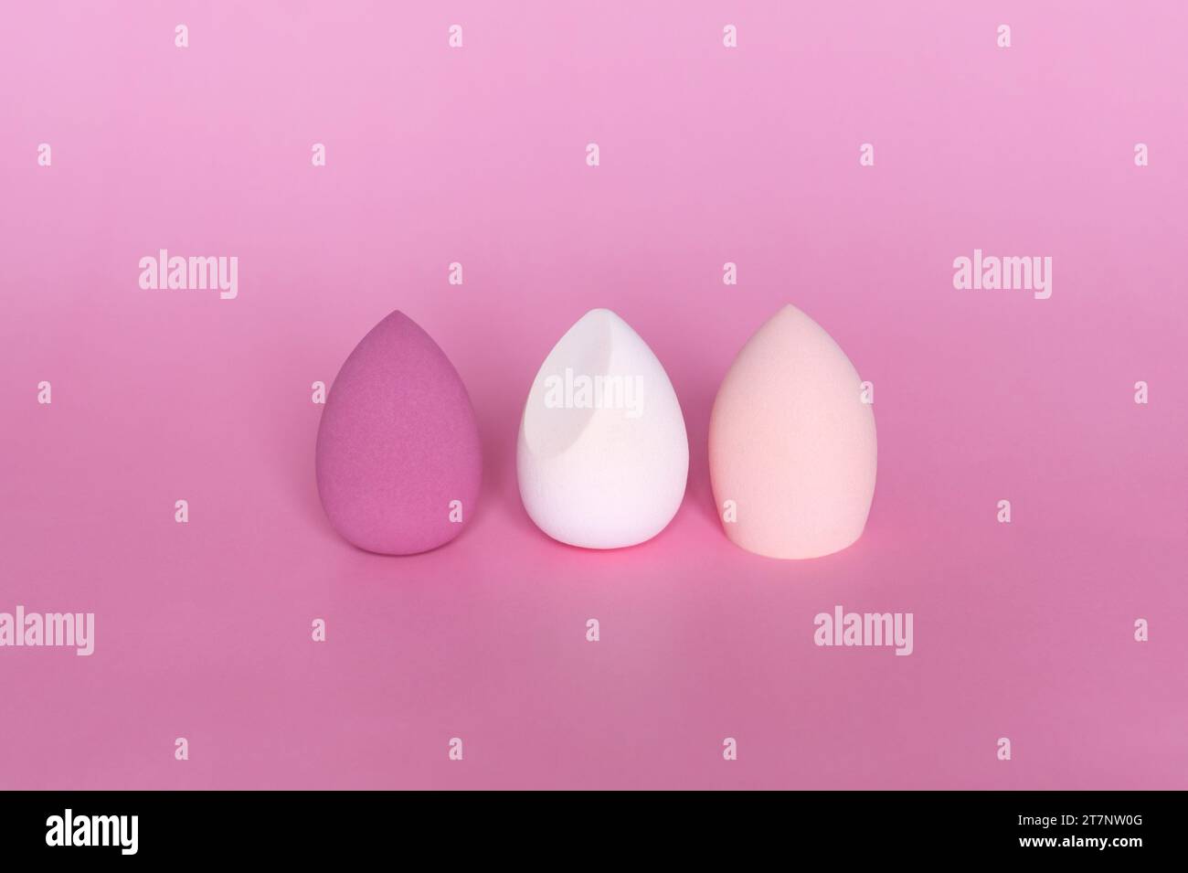 Three colorful beauty blenders or makeup sponges on pink background. Cosmetic tool concept. Stock Photo