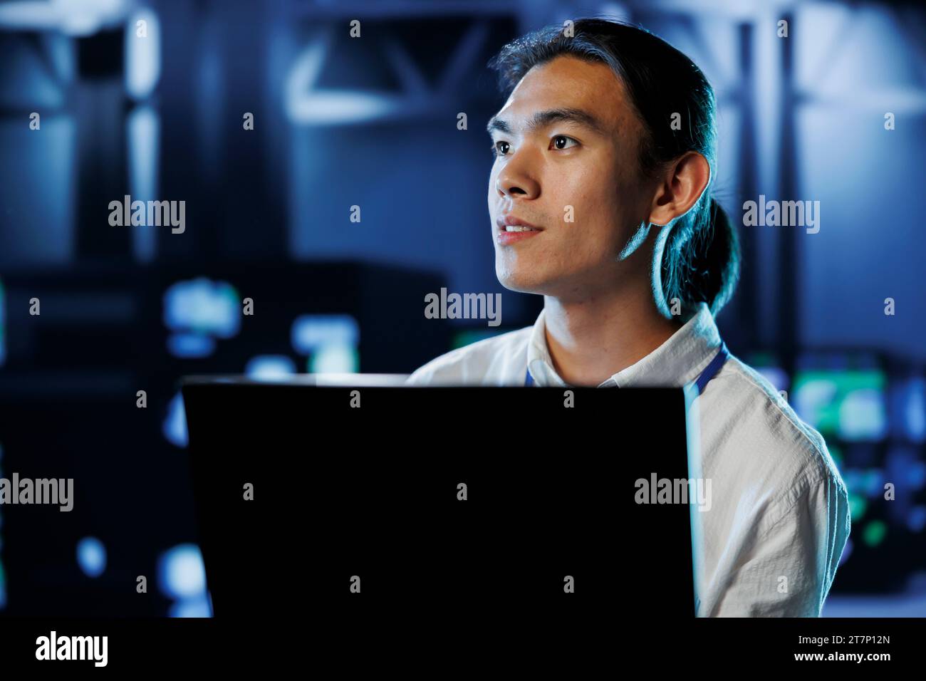 Licensed technician between server hub rows providing processing resources for businesses worldwide. Trained specialist fixing data center mainframes tasked with managing massive databases Stock Photo