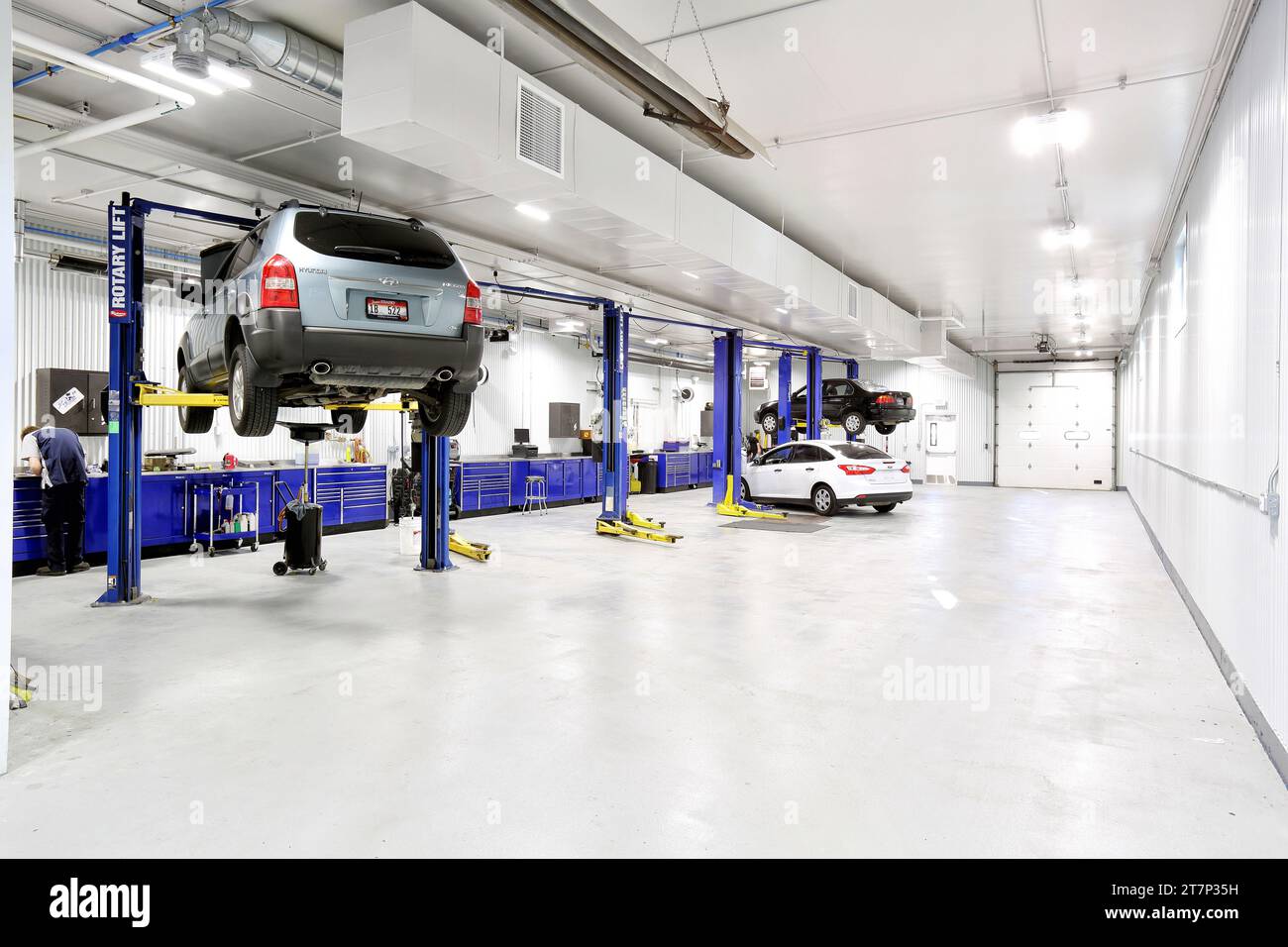 Cars lifted up on hydraulic lifts in a clean new modern car repair shop Stock Photo
