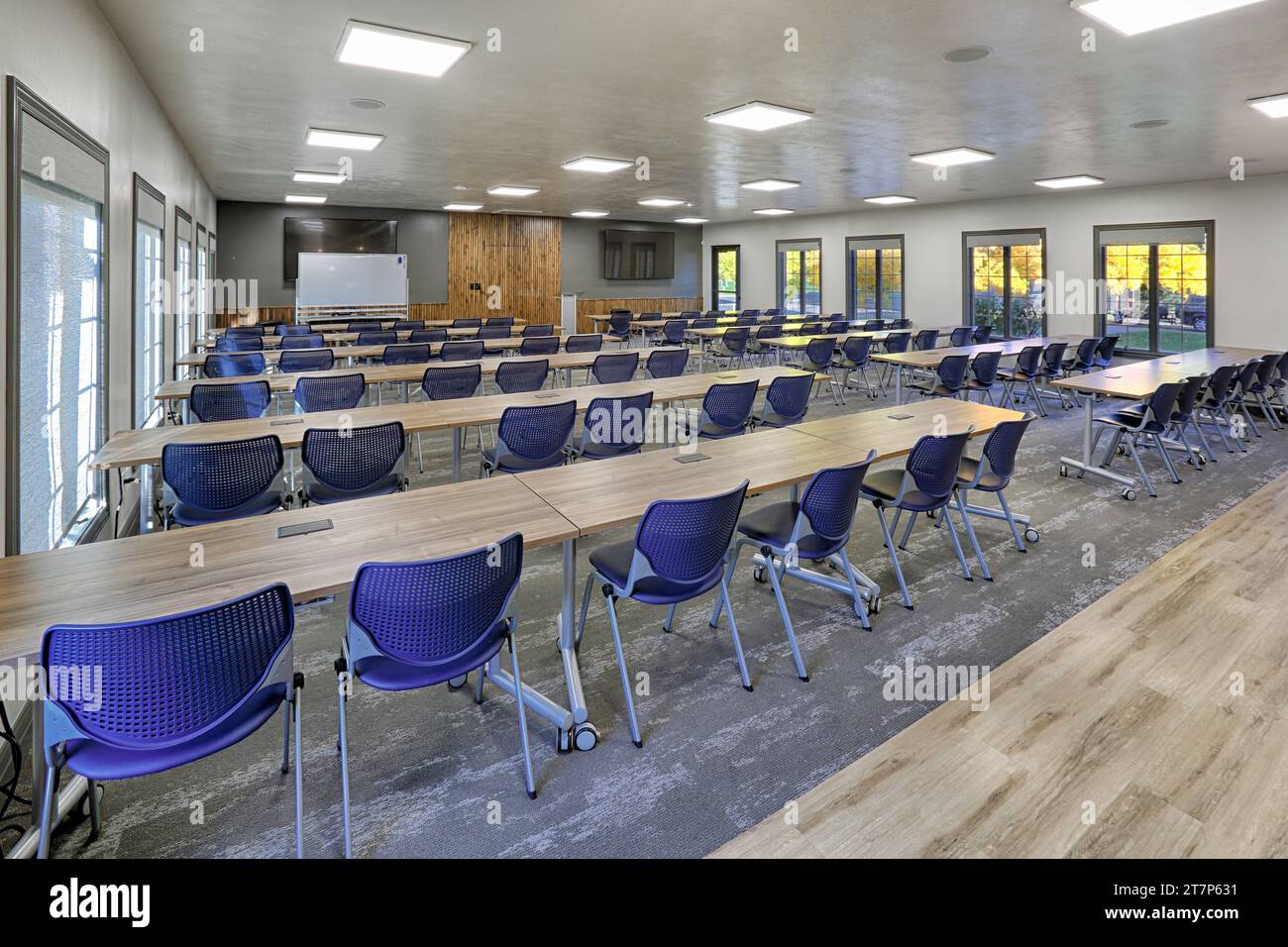 Tables and chairs arranged in rows in a new modern training conference room in a modern corporate office. Stock Photo