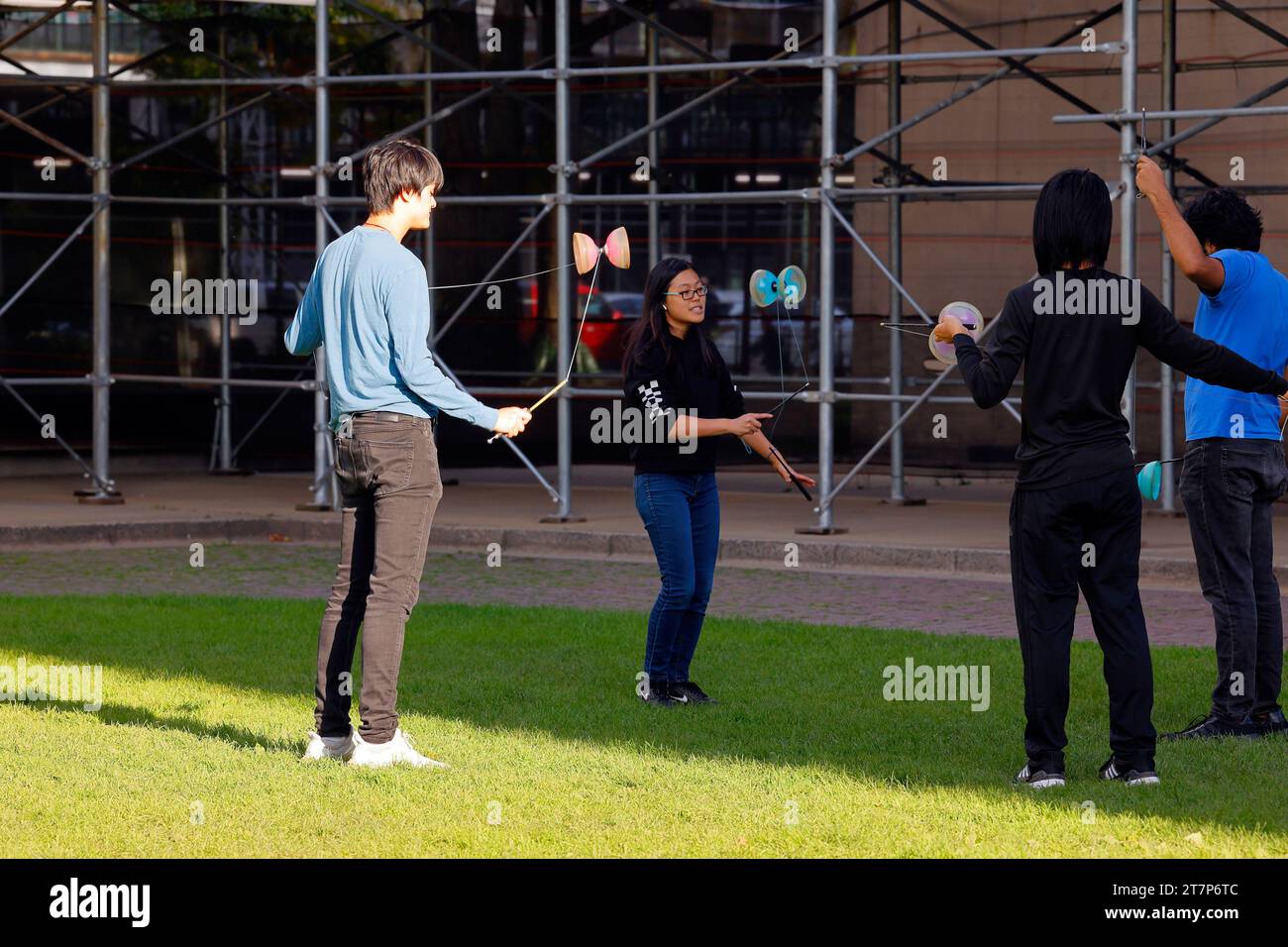 A group of college aged young people spin and practice yo yoing skills with diabolos, or Chinese yoyos. Stock Photo